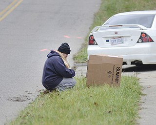 Katie Rickman | The Vindicator.Jamie Bass kneels and prays next to a candle inside a box near where Faith McCullough-Wooster was hit by a school bus on East High Avenue on Thursday, Nov. 13, 2014.  Bass's daughter Alexia Dixon was a close friend of Faith McCullough-Wooster.