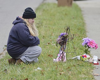 Katie Rickman | The Vindicator.Jamie Bass kneels next to a memorial where Faith McCullough-Wooster was hit by a school bus on East High Avenue on Thursday, Nov. 13, 2014.  Bass's daughter Alexia Dixon was a close friend of Faith McCullough-Wooster.