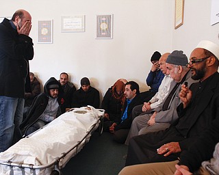A man covers his face and prays near the body of Abdullah Nagi Mahdi at Masjid Al-Khair where members of the community attended the funeral on Friday, Nov. 21, 2014. Mahdi was killed earlier this week during an attempted robbery at his South Avenue store.