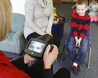        ROBERT K. YOSAY  | THE VINDICATOR..Kathy Collins of the Lions; Sandy Knaus, head of preschool; and Charles Beichner, as he gets his eyes tested with the SPOT VISION SCREENING DEVICE .. The Boardman Lions Club purchased a Spot Vision Screening Device and printer for over $7000 and now offers its services to local pre-school, kindergarten and first-grade students and teachers..-30-
