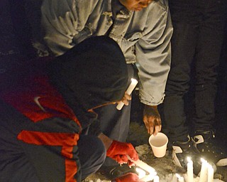 Katie Rickman | The Vindicator.Jackii Edwards of Youngstown leans down next to David McCullough 11, the brother of Faith McCullough-Wooster as they light candles at her vigil on Wednesday, Nov. 19, 2014.