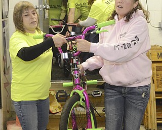 Katie Rickman | The Vindicator.Monica Grachanin on left and Michelle Scott carry a bike into the back room of Masters Bar and Grill for Shots for Tots on Wednesday, Nov. 19, 2014.