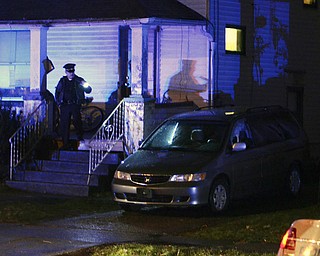 Katie Rickman | The Vindicator .A police officer surveys the scene of a suspected homicide on the 700 block of Lexington Avenue in Youngstown Sunday night. The drivers side window of the vehicle was shot out of the vehicle.