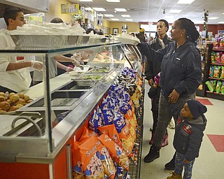 Katie Rickman | The Vindicator.Celeste Berry of Youngstown holds the hand of her grandson Kenneth Miller 2 and reaches for a free turkey meal at the Downtown Circle Deli on West Federal Street in Youngstown on Sunday, Nov. 23, 2014.