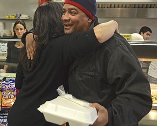 Katie Rickman | The Vindicator.Patrick Wells holds a turckey dinner in one hand as he hugs Fidan Musleh who's husband own the Downtwo n Circle Deli- he thanks.  Fidan was happy to serve the free meals saying " It feels good to give back to the community."