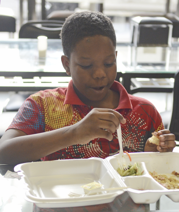 Katie Rickman | The Vindicator.Sage Hallman 10, of Youngstown eats a turkey dinner at Downtown Circle Deli where volunteers served over 200 free dinners on Sunday, Nov. 23, 2014.