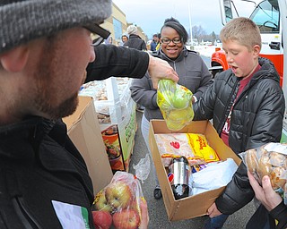 Jeff Lange | The Vindicator  Jacob Barreto (left) places apples in Cynthia Oakley's (center) box as a volunteer assists in carrying the load, Saturday afternoon at Wilson Middle School during the Day of Hope.