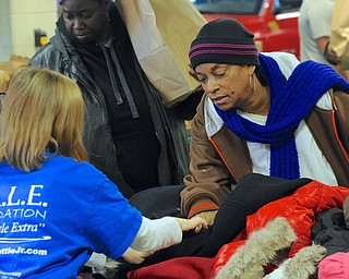 Jeff Lange | The Vindicator  Philense Benson of Warren (right) get help from Mackenzie Gross (left) in determining the size of a coat, Saturday afternoon in Warren during the D.A.L.E. Foundation Thanksgiving Giveaway.