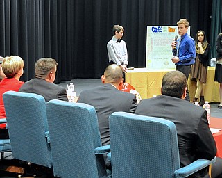Jeff Lange | The Vindicator  JD Hall (in blue) presents his group's restaurant titled Cafe on the Bay to the judges as group members Anthony Lucent (left), Gianna Schiavi (right) and Trinity Farrar (far right) stand behind him during Struthers Middle School's "Wildcat Cage" a spinoff of the TV show Shark Tank, Monday afternoon.