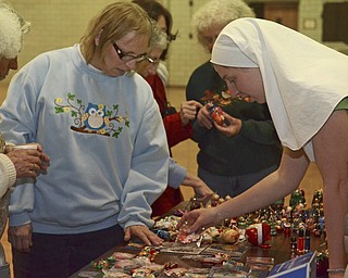 Katie Rickman | The Vindicator.Juliann McLennan of Youngstown seeks the help of Sister Alexandra Klimovich of  Eastern Europe (Belarus) to pick out a special item. Sister Alexandra and Sister Marie are staying in Youngstown and are selling handcrafted items  on Tuesday, Nov. 25, 2014 at the Father Snock Center at Our Lady of Sorrows Parish in Youngstown.