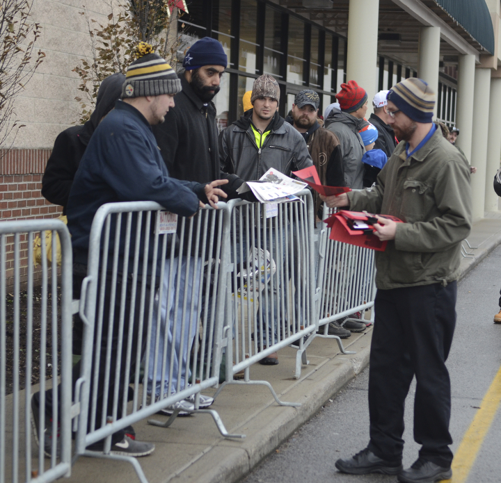 Katie Rickman | The Vindicator.Alvin Carroll of Austintown hands out tickets to customers as they wait in line for Best Buy's Thanksgiving sale to begin at 5 p.m.  on Thursday, Nov. 27, 2014. Many customers waited for hours in the in the cold temperatures to be among the first in the store.
