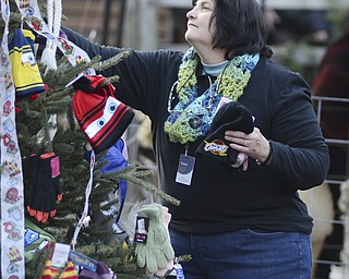 Katie Rickman | The Vindicator.Carol Vigorita the Recreation and Education Manager for Mill Creek MetroParks removes donated hats, scarves and gloves from a tree at Lanterman's Mill during the Olde Fashioned Christmas event on Saturday, Nov. 29, 2014.
