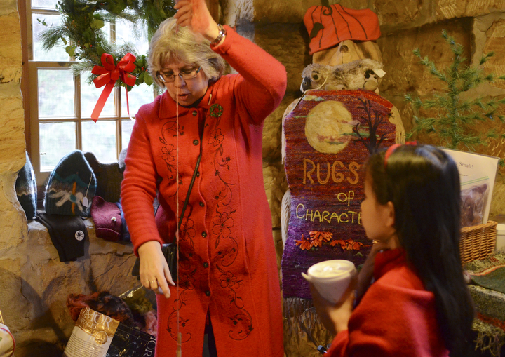 Katie Rickman | The Vindicator.Susan Dexter of New Castle, Pennsylvania spins yarn as Zoey Fick-Mills 9, of Boardman watches during the Olde Fashioned Christmas at Lanterman's Mill at Mill Creek Park on Saturday, Nov. 29, 2014.