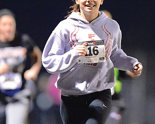 Austintown junior Kelsie Diefenderfer smiles as she leads a pack of runners to the finish line of the 1-mile race during the First Polar Run at Austintown Fitch High School on Sunday night. The event featured two 1-mile races and a 2-mile walk to raise awareness for ALS.