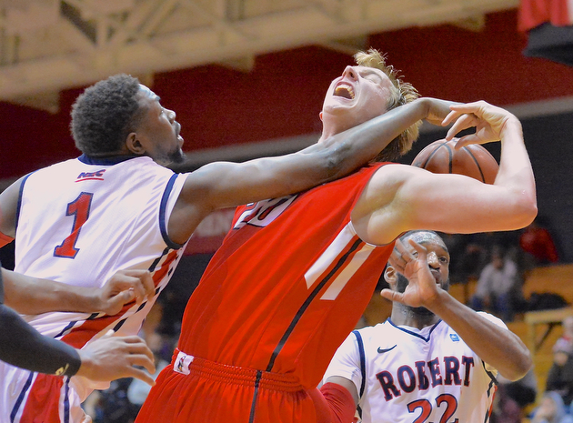 Jeff Lange | The Vindicator  Youngstown's Bobby Hain (center) has the ball hit out of his hand by Robert Morris' Lionel Gomis (1) as he brings down a rebound in the second half of their contest in Moon, PA, Tuesday evening.