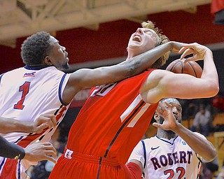 Jeff Lange | The Vindicator  Youngstown's Bobby Hain (center) has the ball hit out of his hand by Robert Morris' Lionel Gomis (1) as he brings down a rebound in the second half of their contest in Moon, PA, Tuesday evening.
