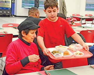 Christopher Noble, a fourth-grader at Struthers Elementary School, serves a turkey dinner to Carrie Ramos of Struthers at the Struthers High School’s second senior-citizens Christmas dinner Thursday afternoon.