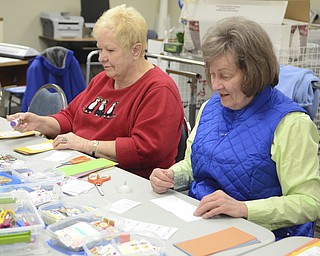 Katie Rickman | The Vindicator.Judy Hack of Austintown on left and Linda Rembowski of Austintown make calendar book marks for veterans  at the Austintown Senior Center on Thursday, Dec. 4, 2014.Mr. Fluffy is an 12-week-old Leonberger dog that spends his days visiting seniors at the center.