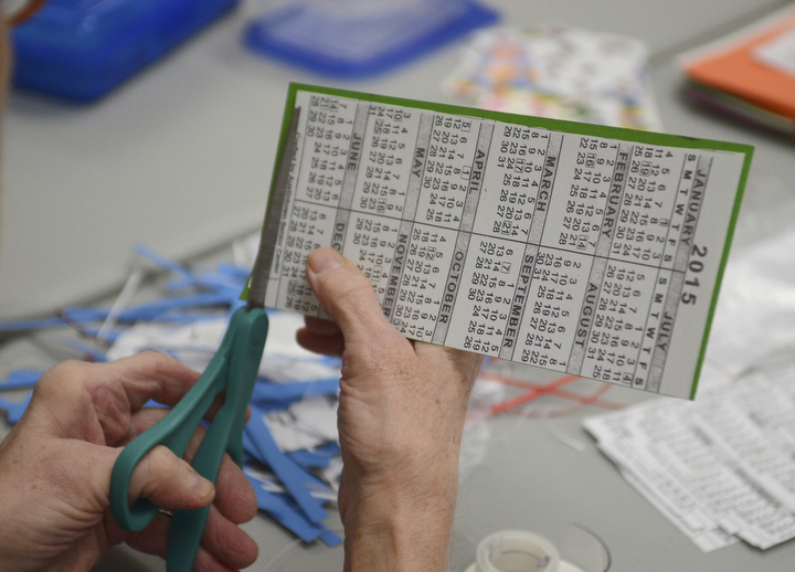 Katie Rickman | The Vindicator.A woman cuts off edges of a calendar bookmark that she and several others have made for veterans  at the Austintown Senior Center on Thursday, Dec. 4, 2014.Mr. Fluffy is an 12-week-old Leonberger dog that spends his days visiting seniors at the center.