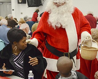 Katie Rickman | The Vindicator.Santa pats Laurie Wade of Youngstown on the back and greets her as Isaiah Christian 6, also of Youngstown, looks up at him during the senior citizens dinner at Struthers High School on Thursday, Dec. 4, 2014.
