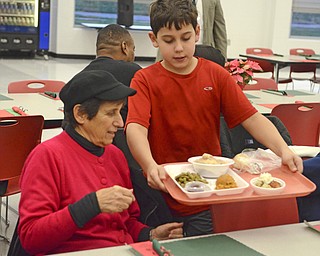 Katie Rickman | The Vindicator.Christopher Noble 10, a fourth-grader at Struthers Elementary School serves food to Carrie Ramos of Struthers at the senior citizens dinner at Struthers High School on Thursday, Dec. 4, 2014.