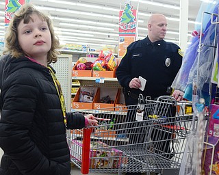Alyson Mitchum, 9, of Youngstown and Officer Medveck search the toy aisle during Shop with a Cop at Kmart in Boardman on Dec. 6. Mitchum said she was looking for How To Train Your Dragon and Skylander toys for her brother.