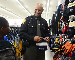 Deputy Art Thompson and Devonte' Clay, 12, of Youngstown look through the sports clothes during Shop with a Cop at Kmart in Boardman on Dec. 6. "Let me show you what you're supposed to wear," Thompson said referring to the Cowboys hat. "A real man wears Steelers," replied Clay.
