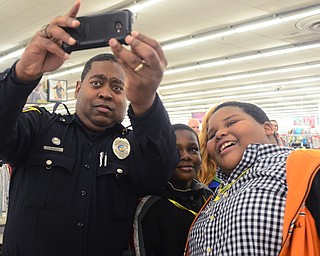 Officer Malik Mostella takes a picture with Malik Rowe, 10, center, and Anthony Harrison, 11, right, of Youngstown during Shop with a Cop at Kmart in Boardman on Dec. 6.