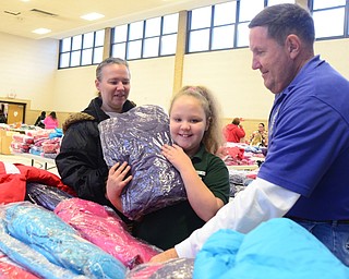 Cierra Craven, 8, of Youngstown, picks out her coat with the help of her mom Melissa, left, and Gary Reel, right, of the Austintown Rotary Club at the Salvation Army in Youngstown on Dec. 6. "Kids get so excited when they have a choice of colors," Reel said. "It's a great experience."