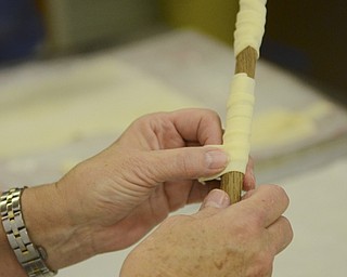 Katie Rickman | The Vindicator.A volunteer at Bethel Lutheran Church wraps dough around a dowel rod to make clothespin cookies on Wednesday, Dec. 10, 2014.