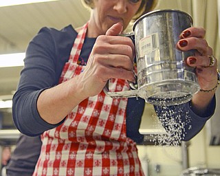 Katie Rickman | The Vindicator.Delaine DeChellis sprinkles powdered sugar on fresh clothespin cookies at Bethel Lutheran Church on Wednesday, Dec. 10, 2014.