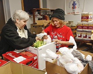        ROBERT K. YOSAY  | THE VINDICATOR..Pat Hughes and Mary Ann Hughes ( no relation)  fill fresh vegetables and food into boxes ...Canned goods, condiments, bread and boxed dinners line 12 tables inside Lake Milton Presbyterian Church..ItÕs enough to provide 20 families in the Jackson-Milton community with groceries for the holidays. .For nearly 30 years, Murle and Kaye McLaughlin have been organizing the effort to help those in need.