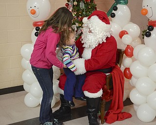 Katie Rickman | The Vindicator.Kayla Rouns 11 passes her sister Aalyah 2 to Santa for a photo during the Struthers Christmas event on Dec 11, 2014. Aalyah's reaction was one of crying and a not so happy photo op.