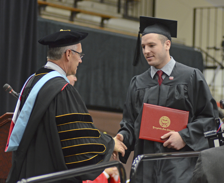 Katie Rickman | The Vindicator.Kory T. Hopkinson shakes the hand of Jim Tressel, President of YSU after receiving his Bachelor of Science in Business Administration degree during commencement at Youngstown State University on Sunday, Dec. 14, 2014 at the Beeghly Center.