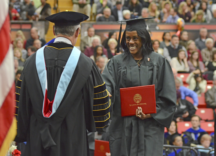 Katie Rickman | The Vindicator.Shalonda Shenell Farley is all smiles after receiving her Associate of Applied Science degree, she shakes the hand of Jim Tressel at Youngstown State University on Sunday, Dec. 14, 2014 at the Beeghly Center.