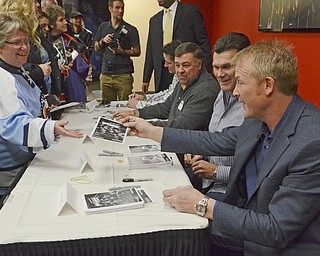 Katie Rickman | The Vindicator.Barbara Carney of Struthers (on left) takes a signed photo from Troy Loney and other former Penguin players at the Covelli Centre on Dec. 19, 2014.