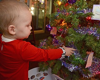 Katie Rickman | The Vindicator.Isabella Grace McDermott, 1, grabs an ornament on the Giving Tree that her mother Kerrigan started to donate to a non profit in Warren.