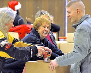Jeff Lange | The Vindicator  Maryola Stemple of Warren (center) smiles as she and Brenda Zannetakk of Lordstown place non-perishable food items into the box of Sgt. Thomas Clunen of Youngstown, Wednesday morning at at the UW Local 1112 Union Hall
