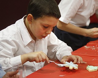        ROBERT K. YOSAY  | THE VINDICATOR..Andrew Salupo....  smooths on icing .. on a cookie ..St. Christine students ( 4th grade )  decorate holiday cookies that will be donated to YoungstownÕs Dorothy Day House, which provides emergency shelter and a meal to people down on their luck....-30-