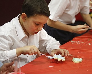        ROBERT K. YOSAY  | THE VINDICATOR..Andrew Salupo....  smooths on icing .. on a cookie ..St. Christine students ( 4th grade )  decorate holiday cookies that will be donated to Youngstown’s Dorothy Day House, which provides emergency shelter and a meal to people down on their luck....-30-