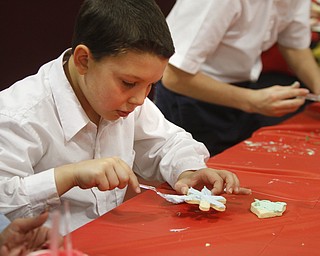        ROBERT K. YOSAY  | THE VINDICATOR..Andrew Salupo....  smooths on icing .. on a cookie ..St. Christine students ( 4th grade )  decorate holiday cookies that will be donated to YoungstownÕs Dorothy Day House, which provides emergency shelter and a meal to people down on their luck....-30-
