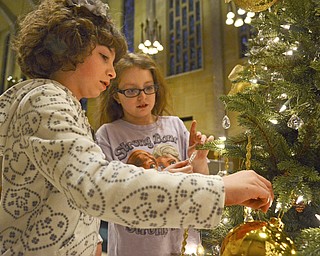Katie Rickman | The Vindicator.Elizabeth Elder 11 of Canfield on left and her friend Ami Slanina 10 of Youngstown place ornaments on one of the trees inside of St. Columba Cathedral as their parents wrap up Christmas decor at the church on Sunday evening.