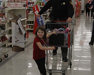 Chuyenne Maxwell (4) of Youngstown pulls a shopping cart full of toys through an isle with Deputy Michael Hunchuck during the Shop with a Cop event at Kmart in Boardman on Saturday morning.  Dustin Livesay  |  The Vindicator  12/20/14  Boardman