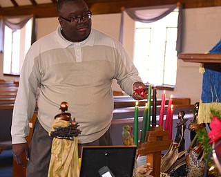 YOUNGSTOWN, OHIO - DECEMBER 22, 2014: Pastor Lewis Macklin lights the seven principles of Kwanza candles Monday afternoon at Holy Trinity Baptist Church. (Photo by David Dermer/Youngstown Vindicator)
