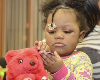 Katie Rickman | The Vindicator.Gianna Henderson plays with the tag of a stuffed animal she received as a gift at the Rescue Mission in Youngstown where the Afro Dogs Motorcycle Club donated gifts to the children on Tuesday, Dec. 23, 2014.
