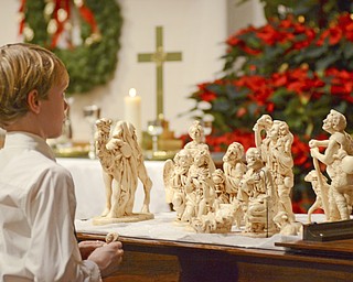 Katie Rickman | The Vindicator.Garrett Morgan,  9 of Canfield holds a small figure of baby Jesus as he places it with the manger scene during the Christmas Eve service at Canfield Presbyterian Church on Dec. 24, 2014.