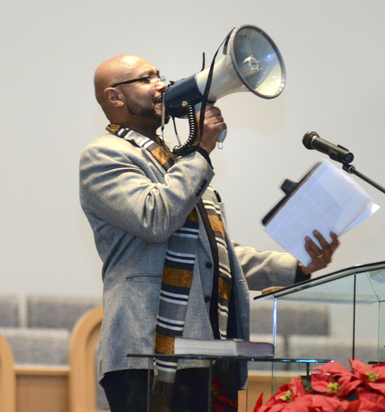 Katie Rickman | The Vindicator.Rev. Kenneth Simon of New Bethel Baptist Church speaks through a mega-phone and chants "black lives matter" and "hands up don't shoot" during the first night of Kwanzaa celebrations at the church on Friday, Dec. 26, 2014.