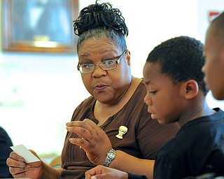 Jeff Lange | The Vindicator  .Barbara Brown (facing) explains what self determination means to 10 year-old Kyle Jenkins of Youngstown who attended the second day of Kwanzaa celebration with his mother Melissa Grier at the East Branch of the Public Library of Youngstown and Mahoning County, Saturday afternoon.
