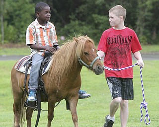 William D. Lewis The Vindicator Lamar McKinney, 8, left, gets a pony ride while William Cunningham of Canfield leads a pony from Barnyard pony rides and petting zoo in canfield during an appreciation picnic at ESA Park apartments on Y-town's Eastside August 5, 2014. The event featured games pony rides, music and food for young residents of the complex.
