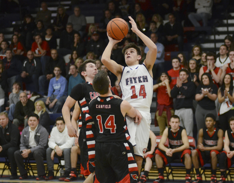 Katie Rickman | The Vindicator.Austintown's  Derek Gunter  (14) goes up for a shot as Canfield's Jake Cummings(11) and Mike Yourstowsky (14) attempt to block him during the second period at Fitch High School on Friday, Jan. 2, 2015.